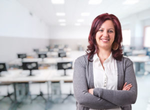Image: smiling female faculty member in front of empty classroom with computers